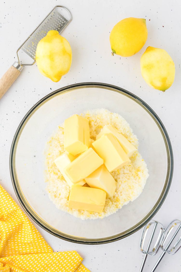 Butter being added to a bowl of sugar and lemon zest.