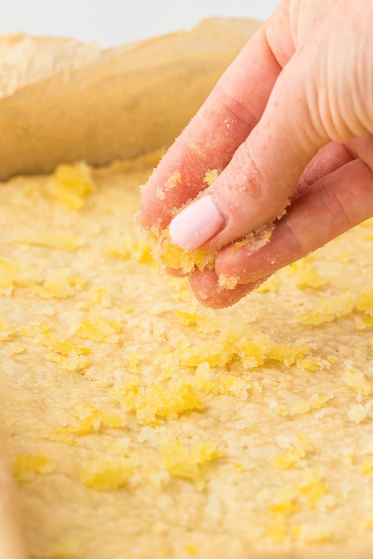 Lemon sugar being sprinkles over the top of shortbread bars.