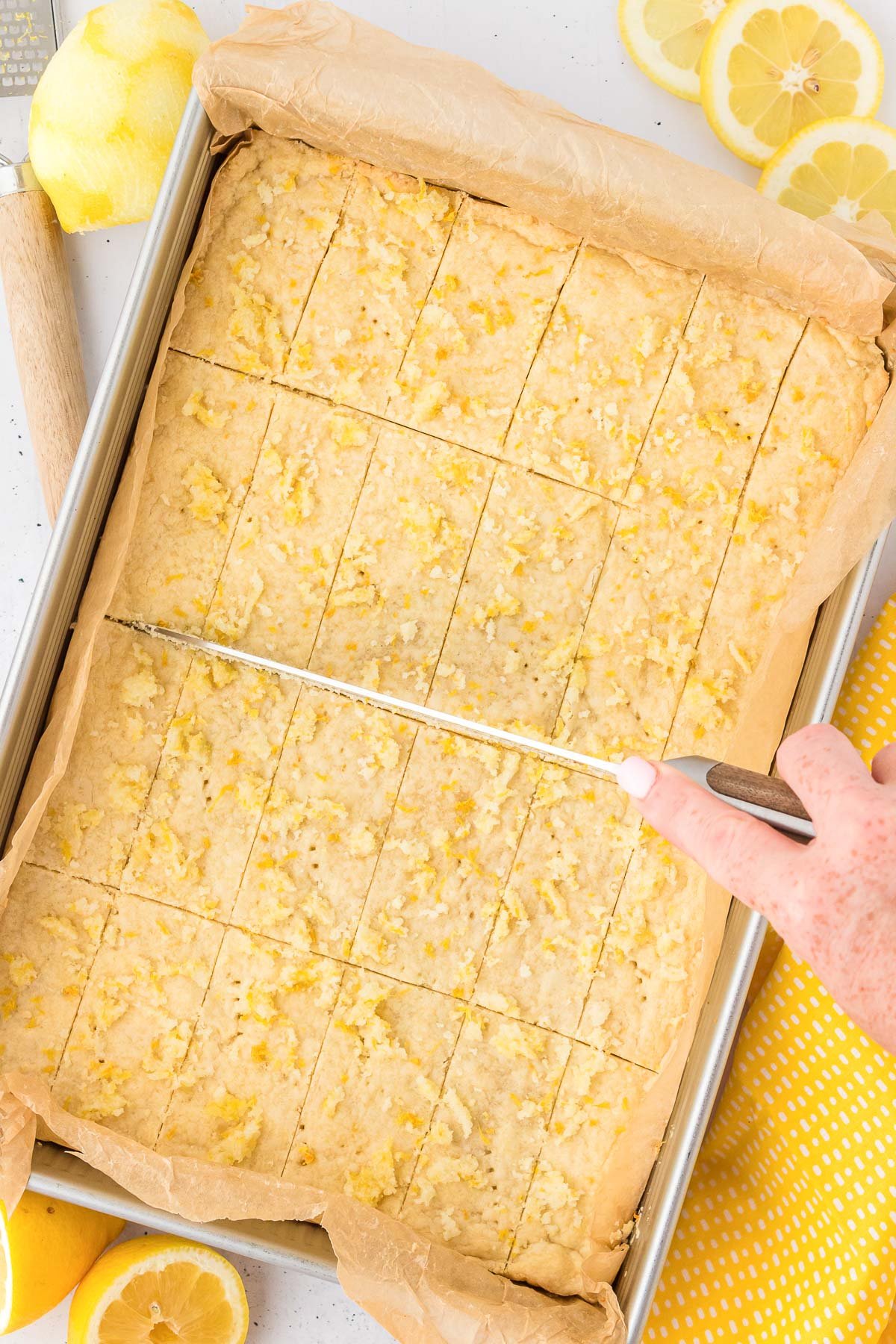 Lemon shortbread bars being cut in a pan.