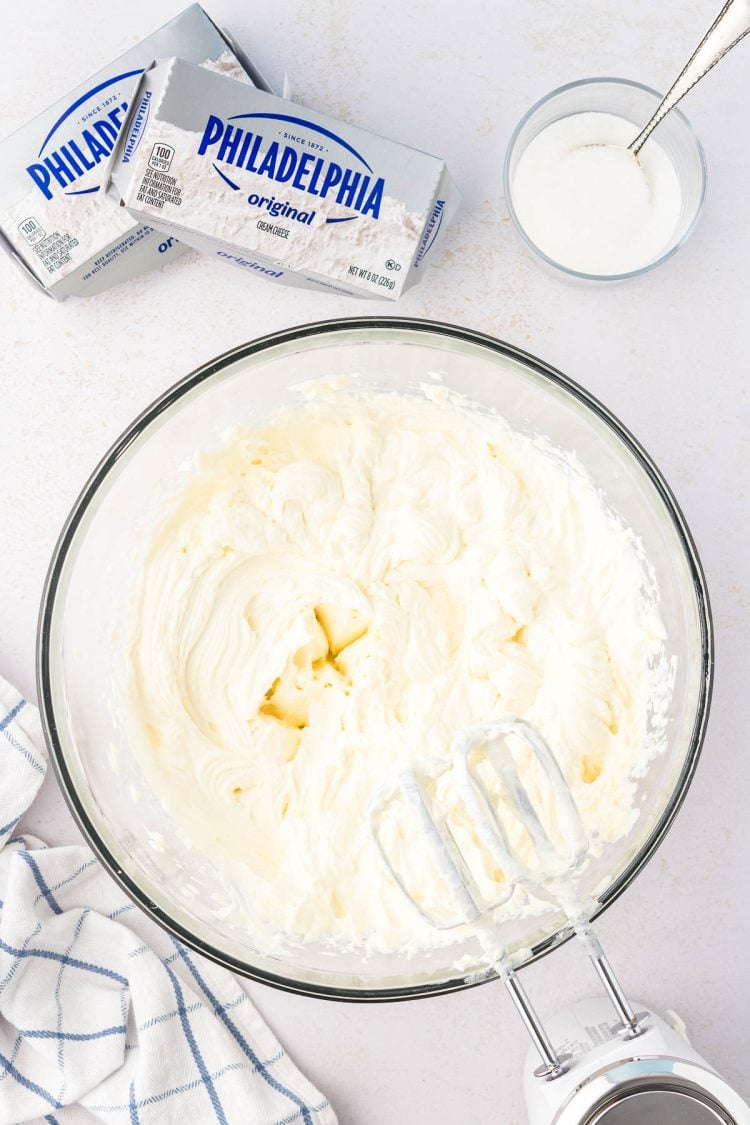 Cream cheese and sugar beaten in a glass mixing bowl.