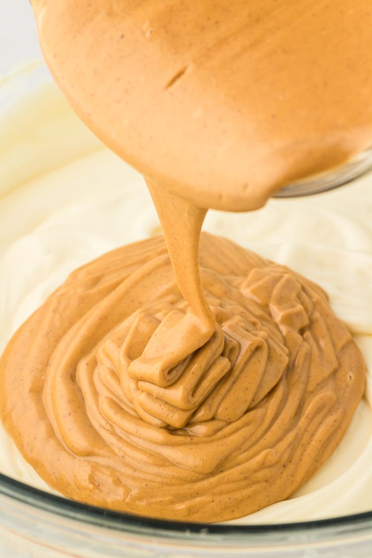 Melted peanut butter being poured into cheesecake mixture.