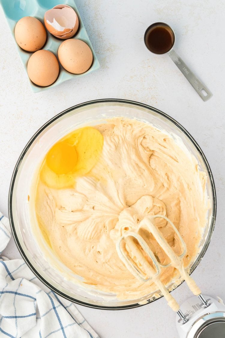 Eggs being mixed into peanut butter cheesecake filling.