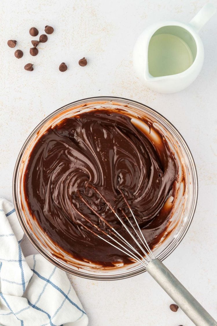 Chocolate ganache being whisked in a glass bowl.