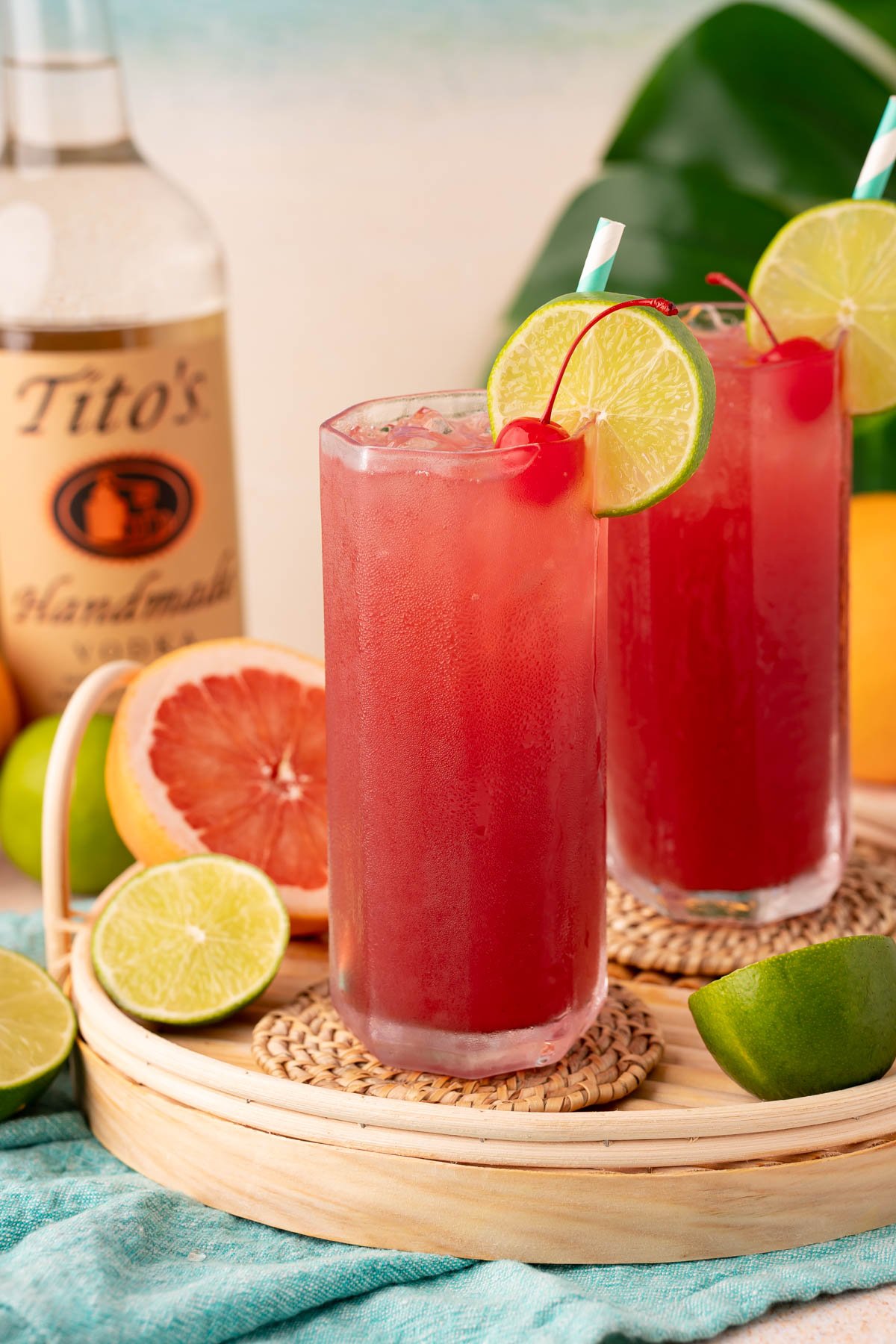 Two sea breeze cocktails on a rattan tray.