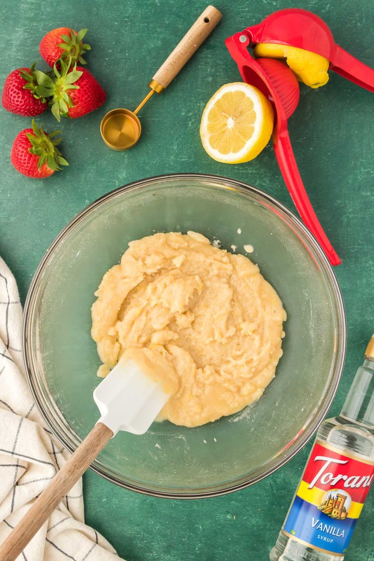 Mixture for strawberries for cobbler being mixed in a bowl.