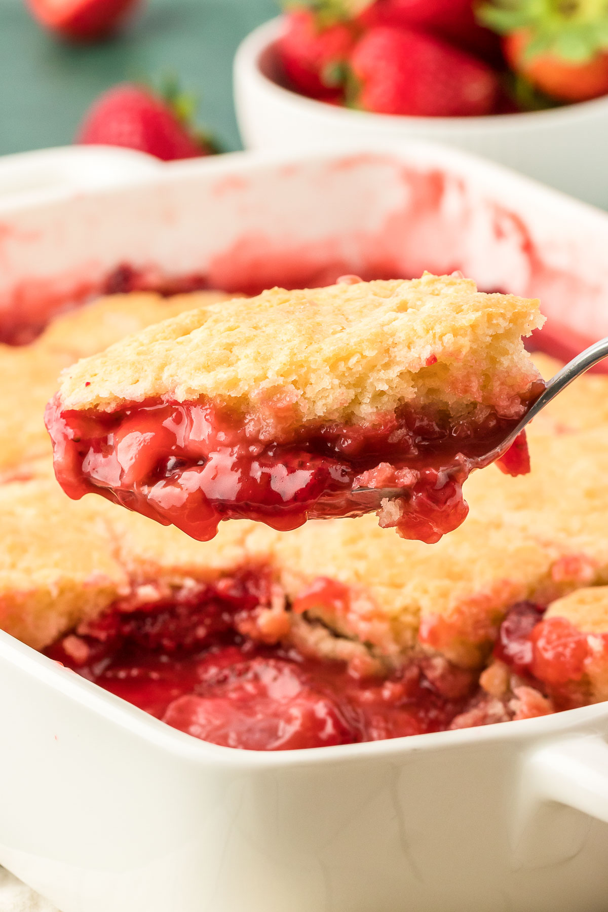 A serving spoon scooping out strawberry cobbler. 
