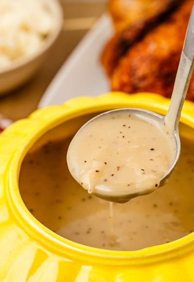 A ladle lifting gravy out of a gravy boat.