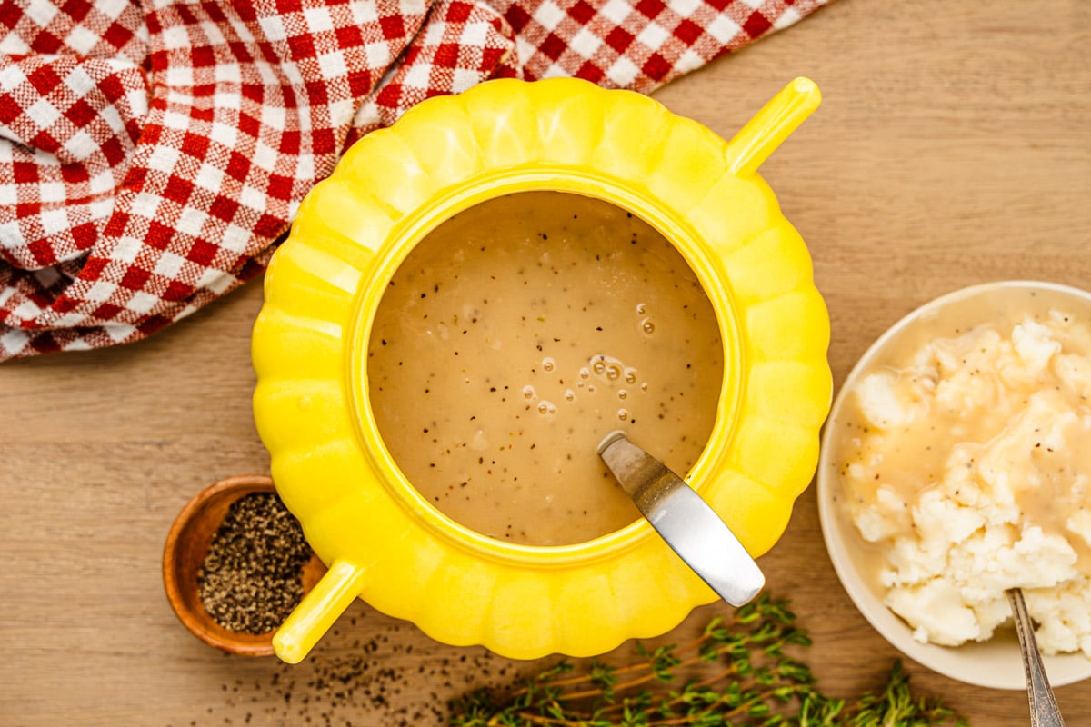 overhead photo of a bowl of a yellow gravy boat on a wooden table.