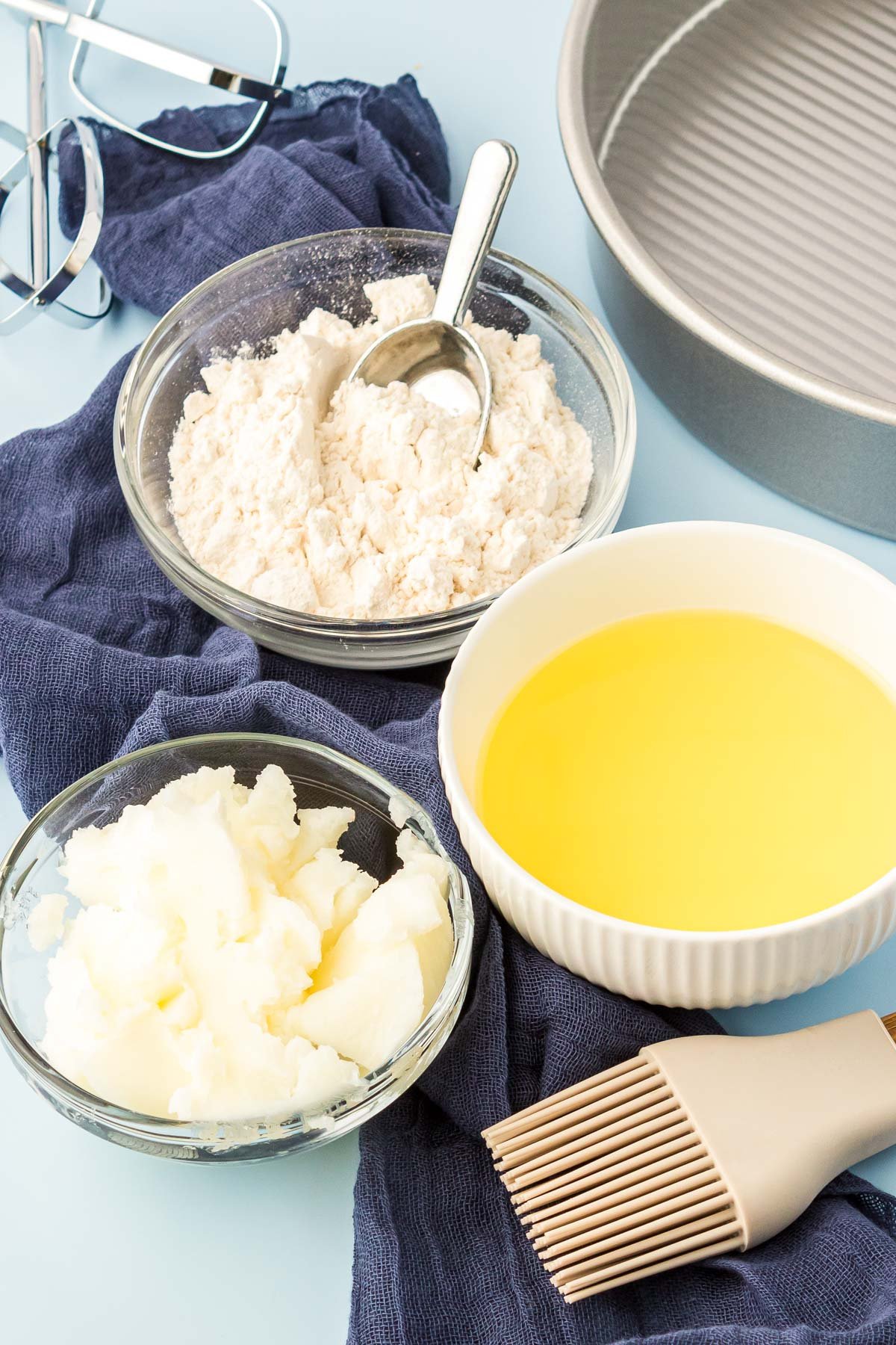 Ingredients to make cake good in prep bowls on a blue surface.