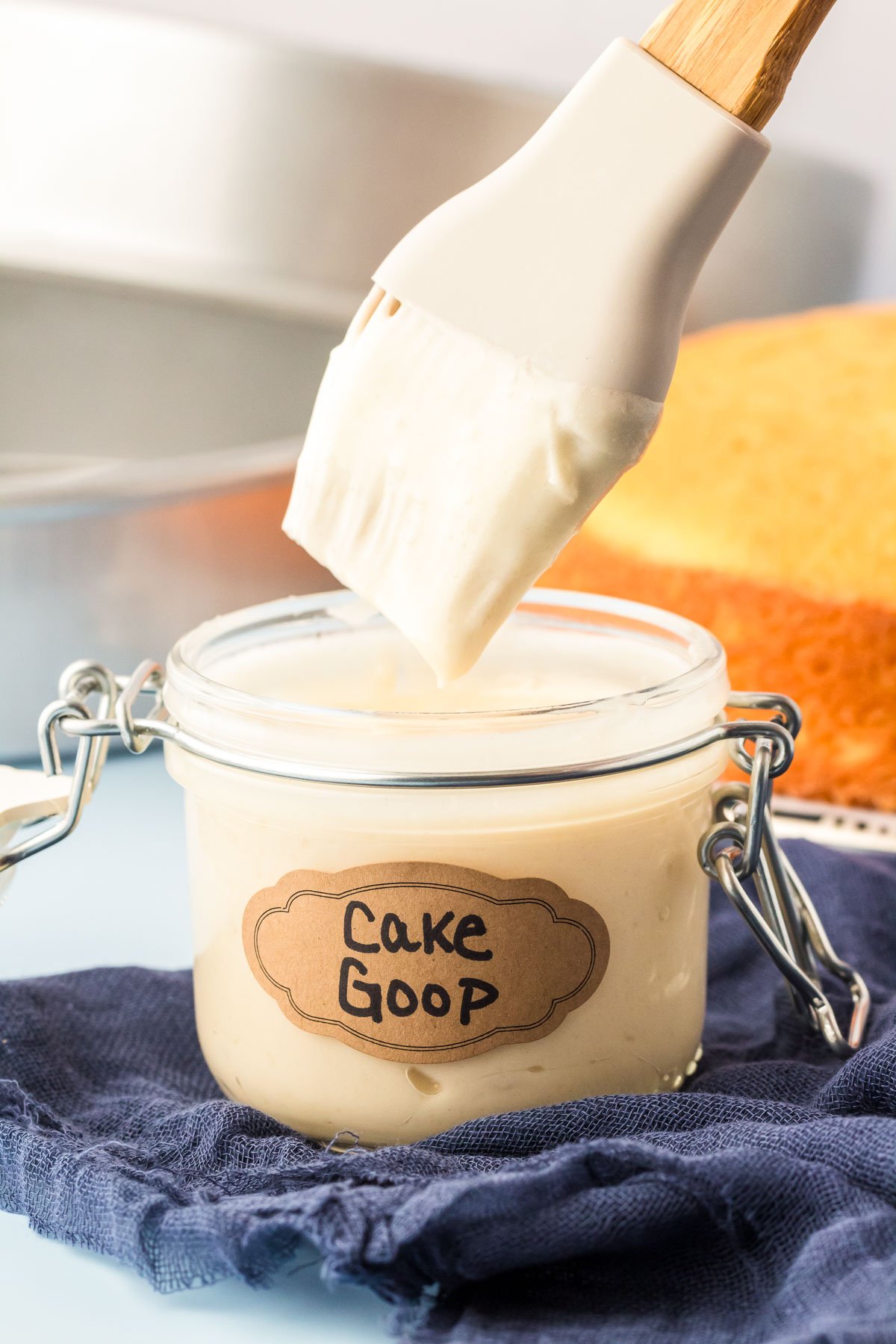 A pastry brush dipping into a jar of cake goop.