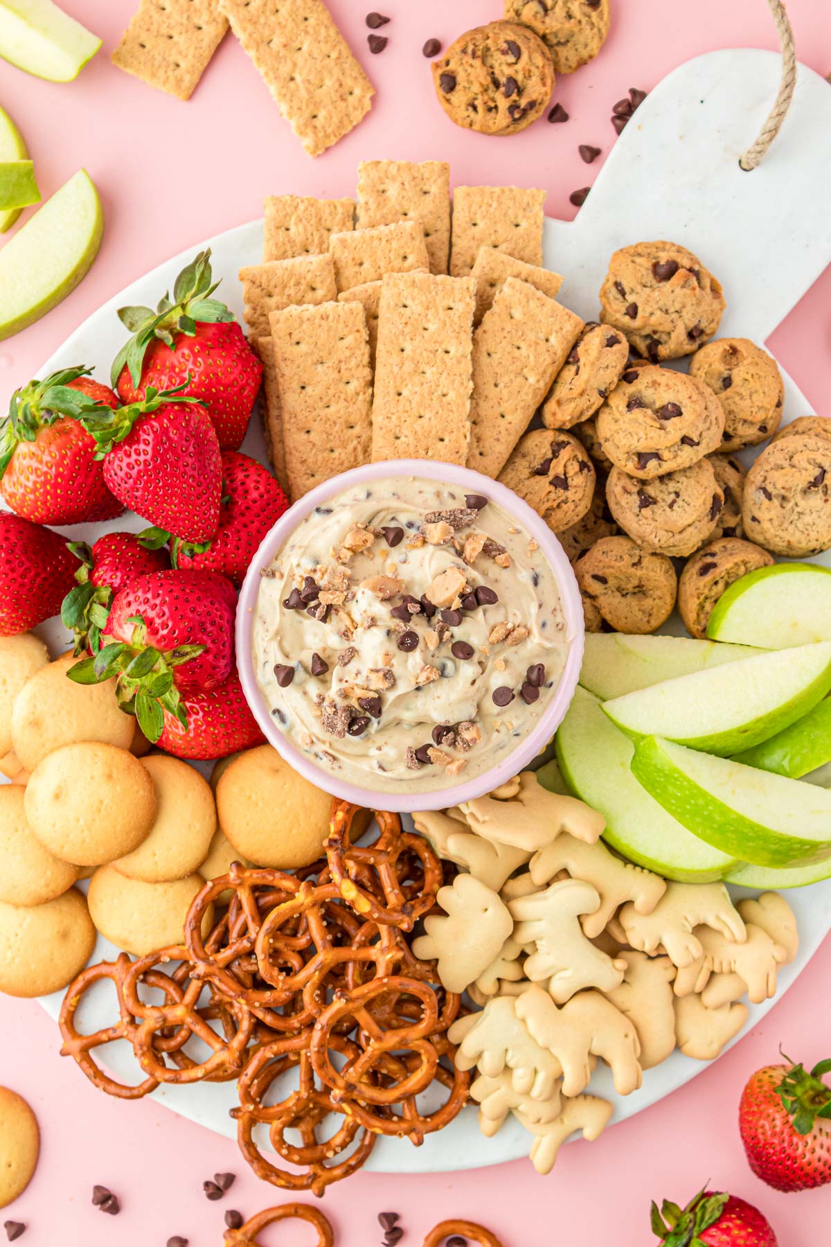 Overhead photo of a party dip board with cookie dough dip, apples, strawberries, cookies, and more!