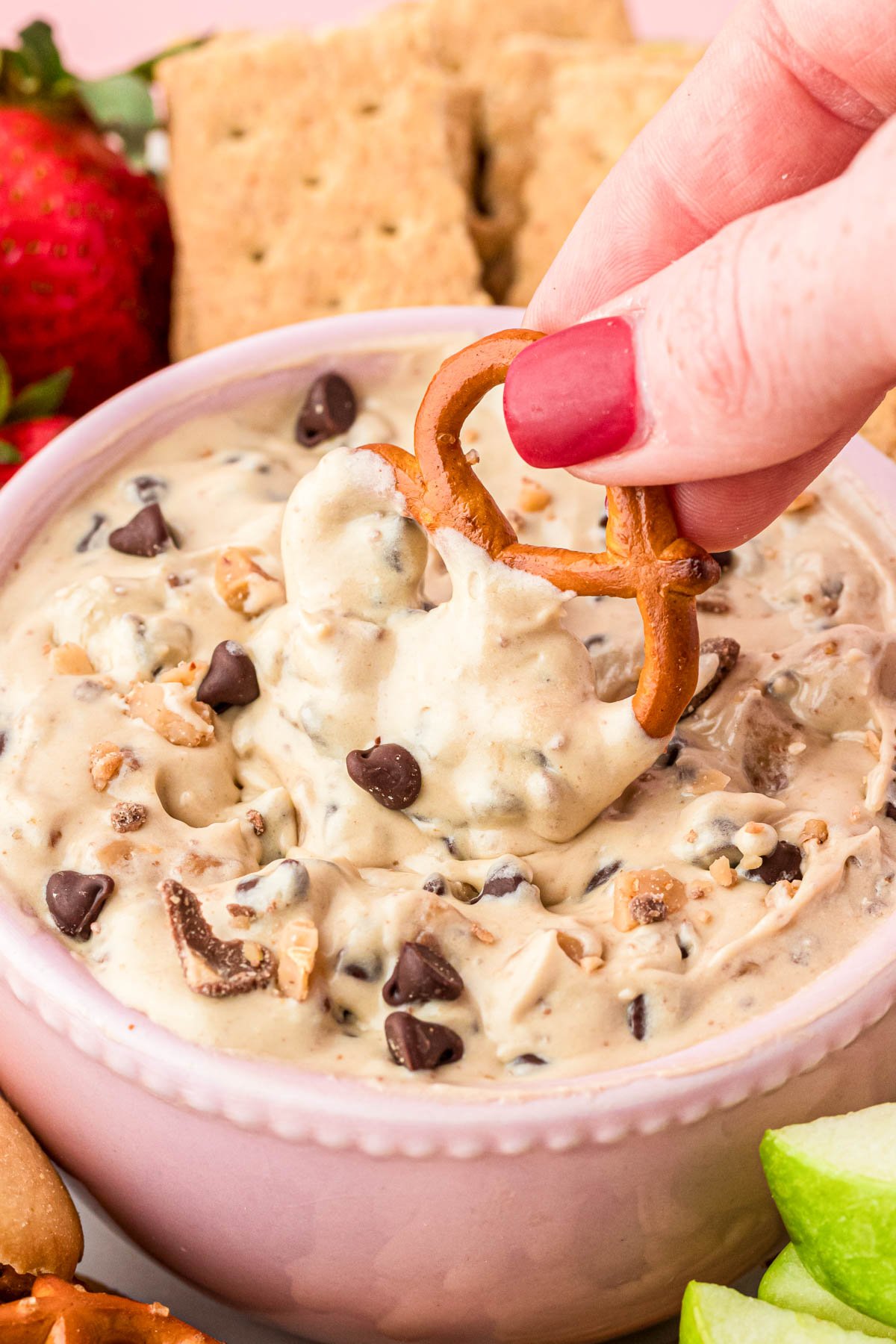 A pretzel being dipped in cookie dip.