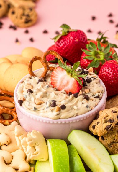 A bowl of chocolate chip dip surrounded bu fruit and cookies for dipping.