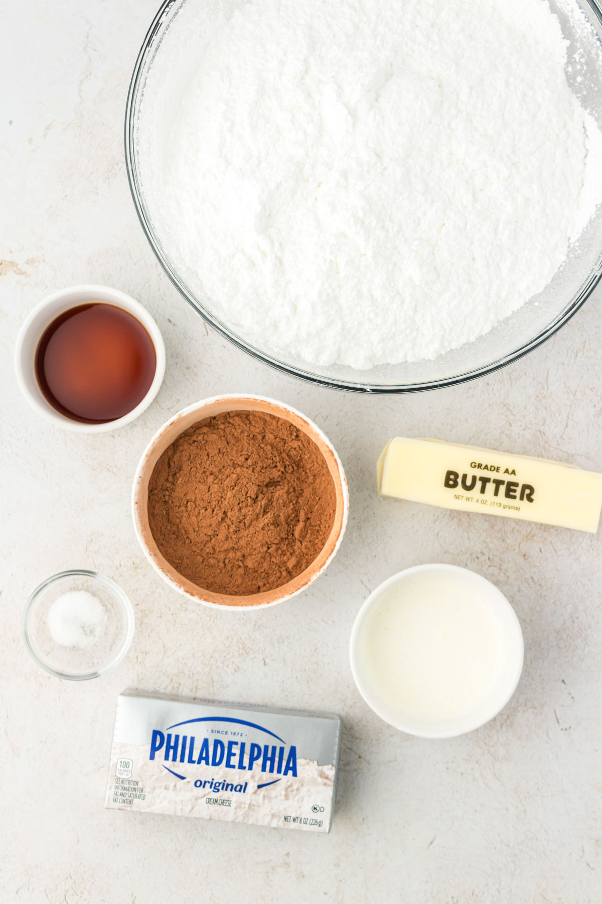 Overhead photo of ingredients to make cream cheese chocolate frosting on a table.