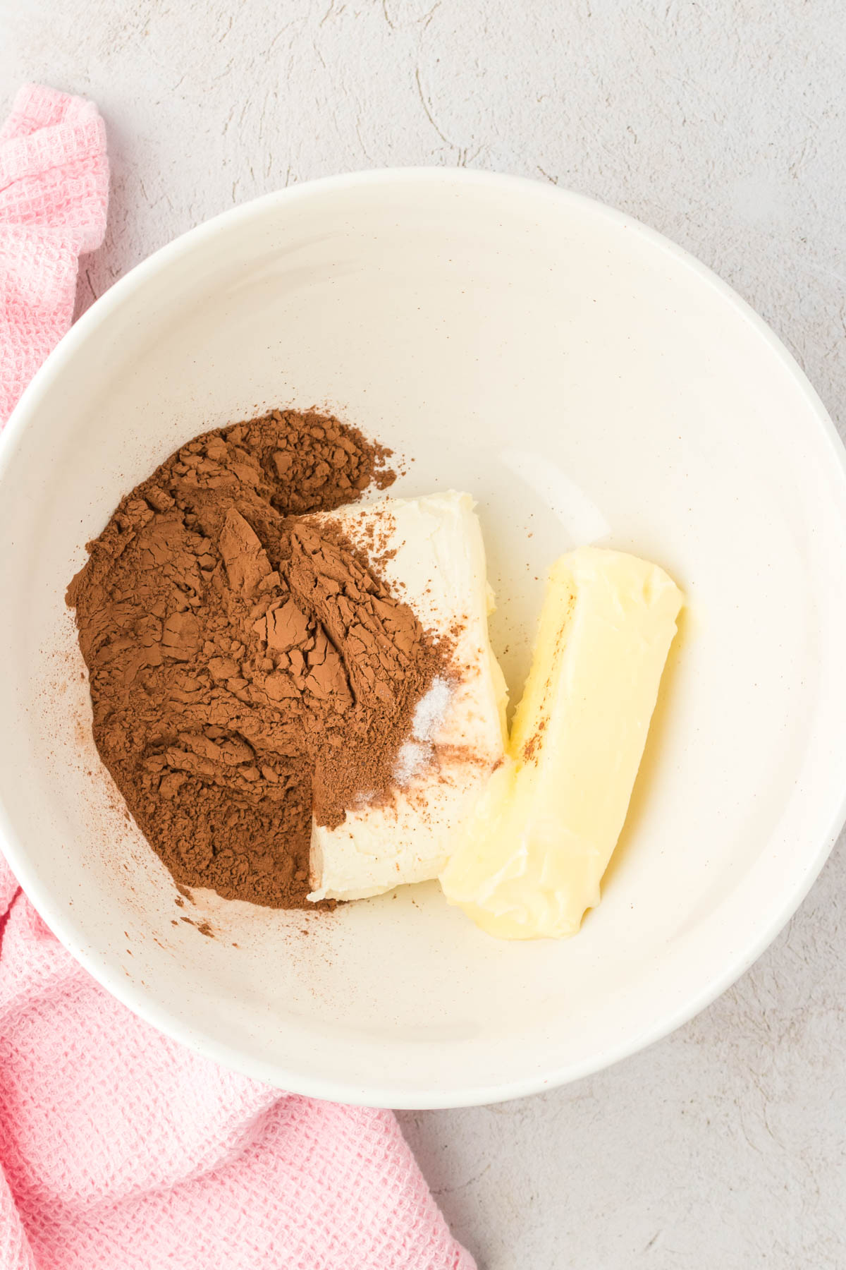 Butter, cream cheese, and cocoa powder in a mixing bowl.