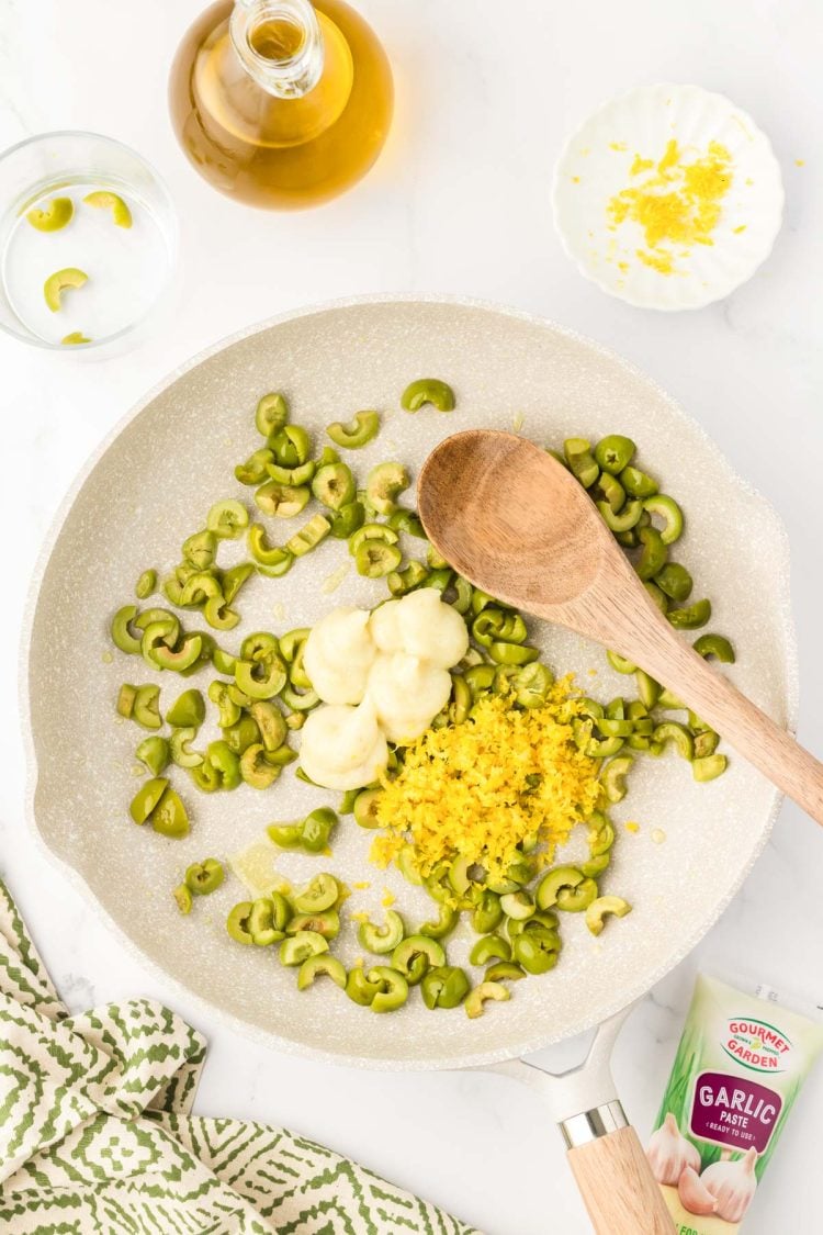 Garlic paste and lemon zest being added to a skillet.