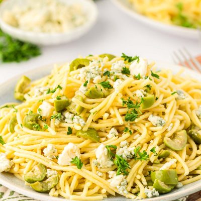 A plate of dirty martini pasta on a wooden board.