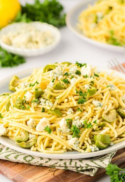 A plate of dirty martini pasta on a wooden board.