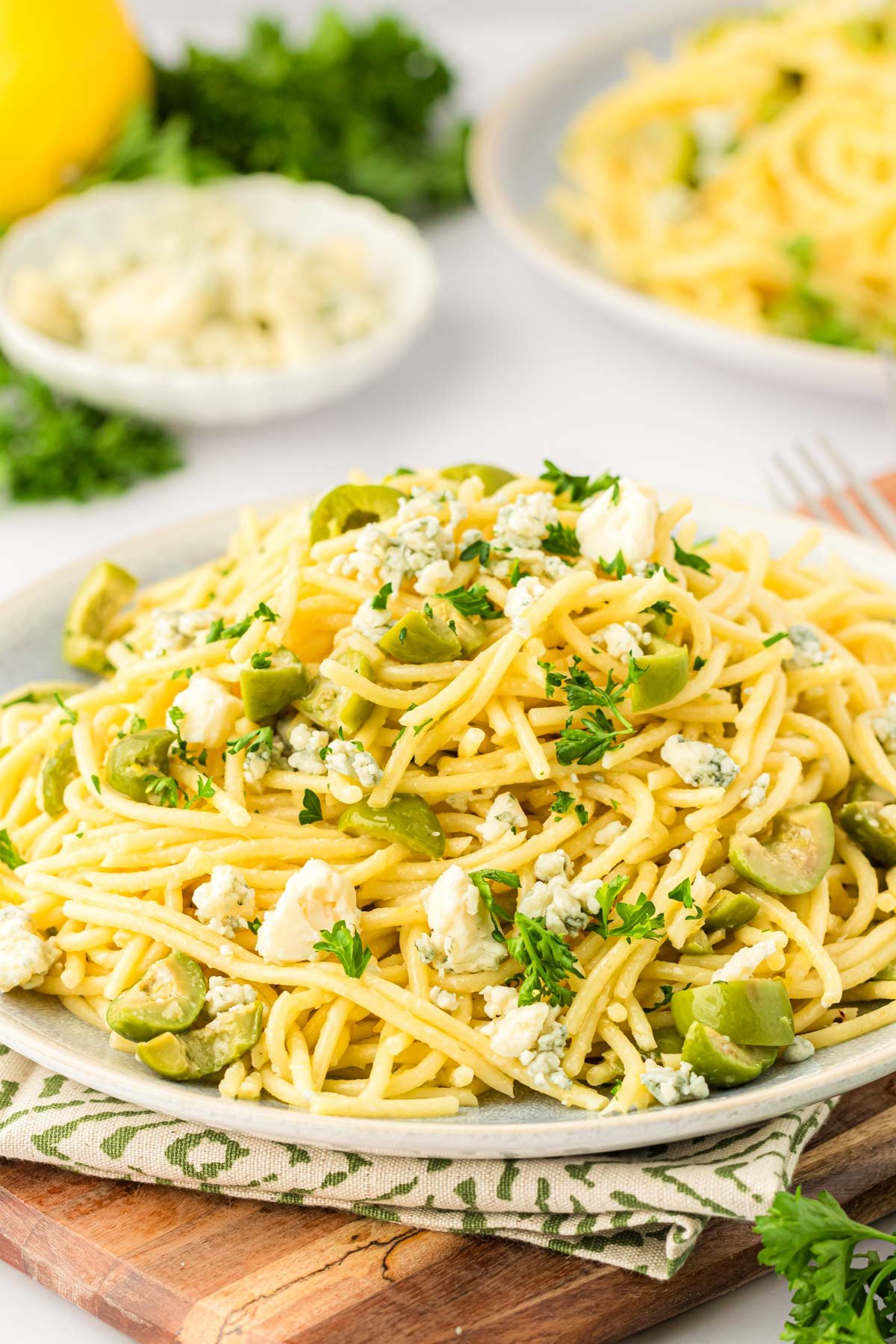 A plate of dirty martini pasta on a wooden board.