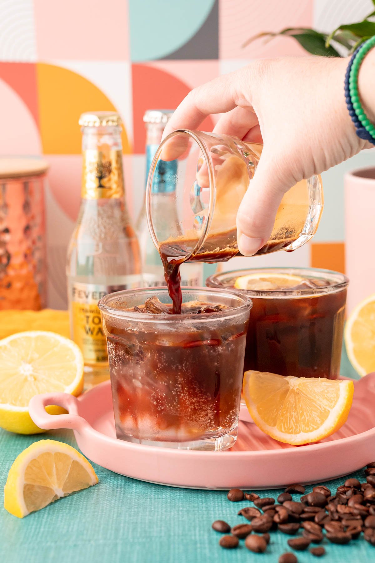 A double shot of espresso being poured into a glass with ice and tonic water.