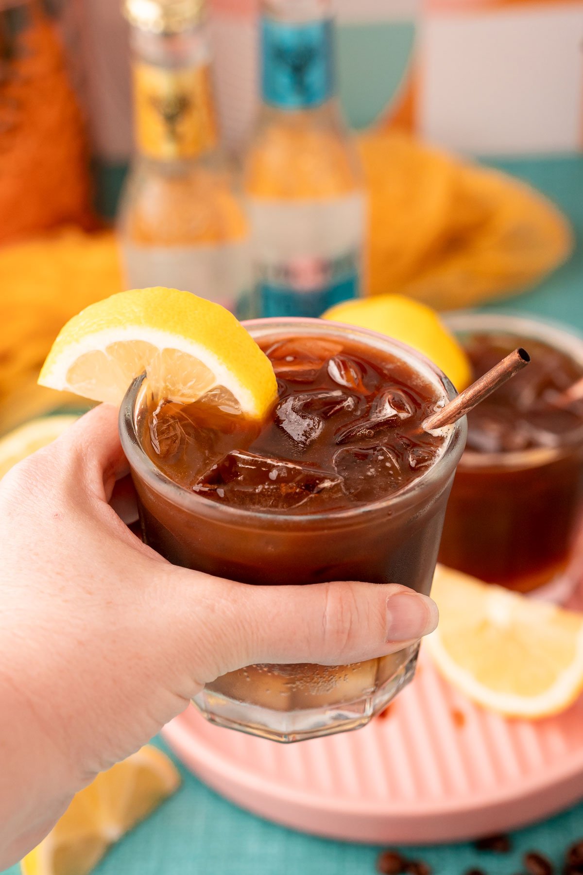 A woman's hand holding a glass of espresso tonic to the camera.