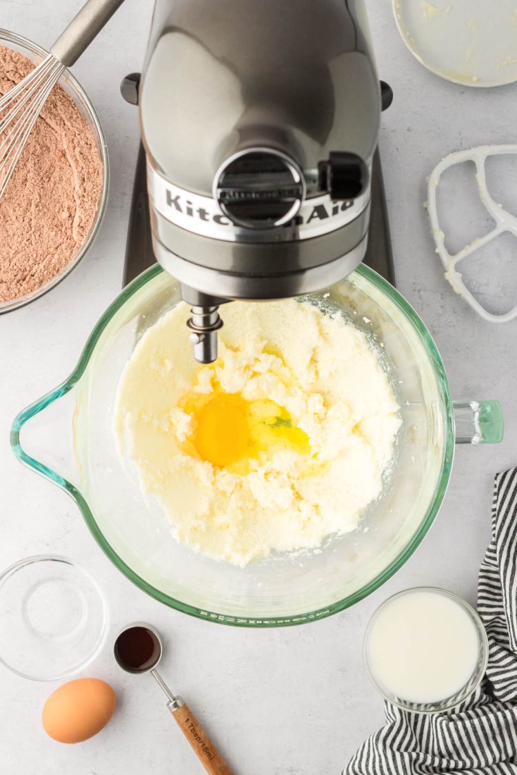 Egg being beat into a cookie dough base in a stand mixer.