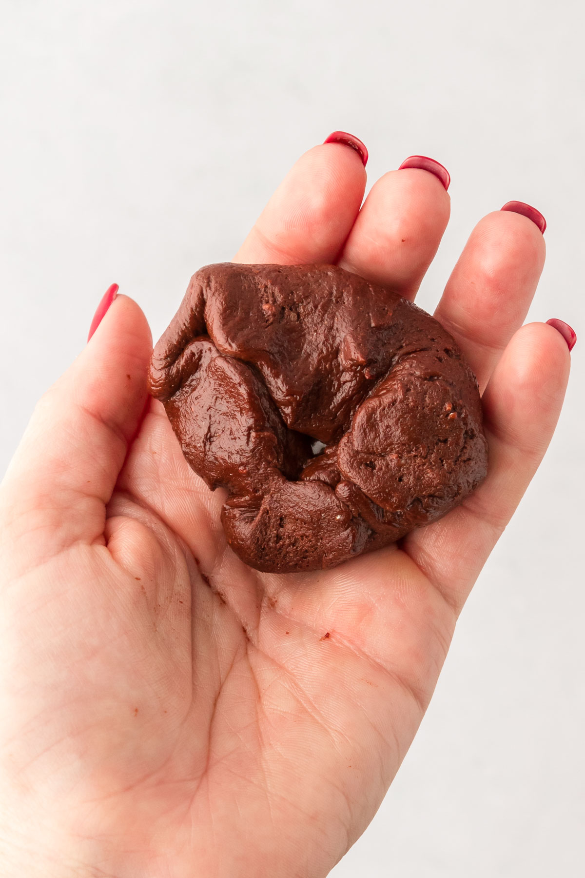 A ball of chocolate cookie dough being wrapped around hot fudge.