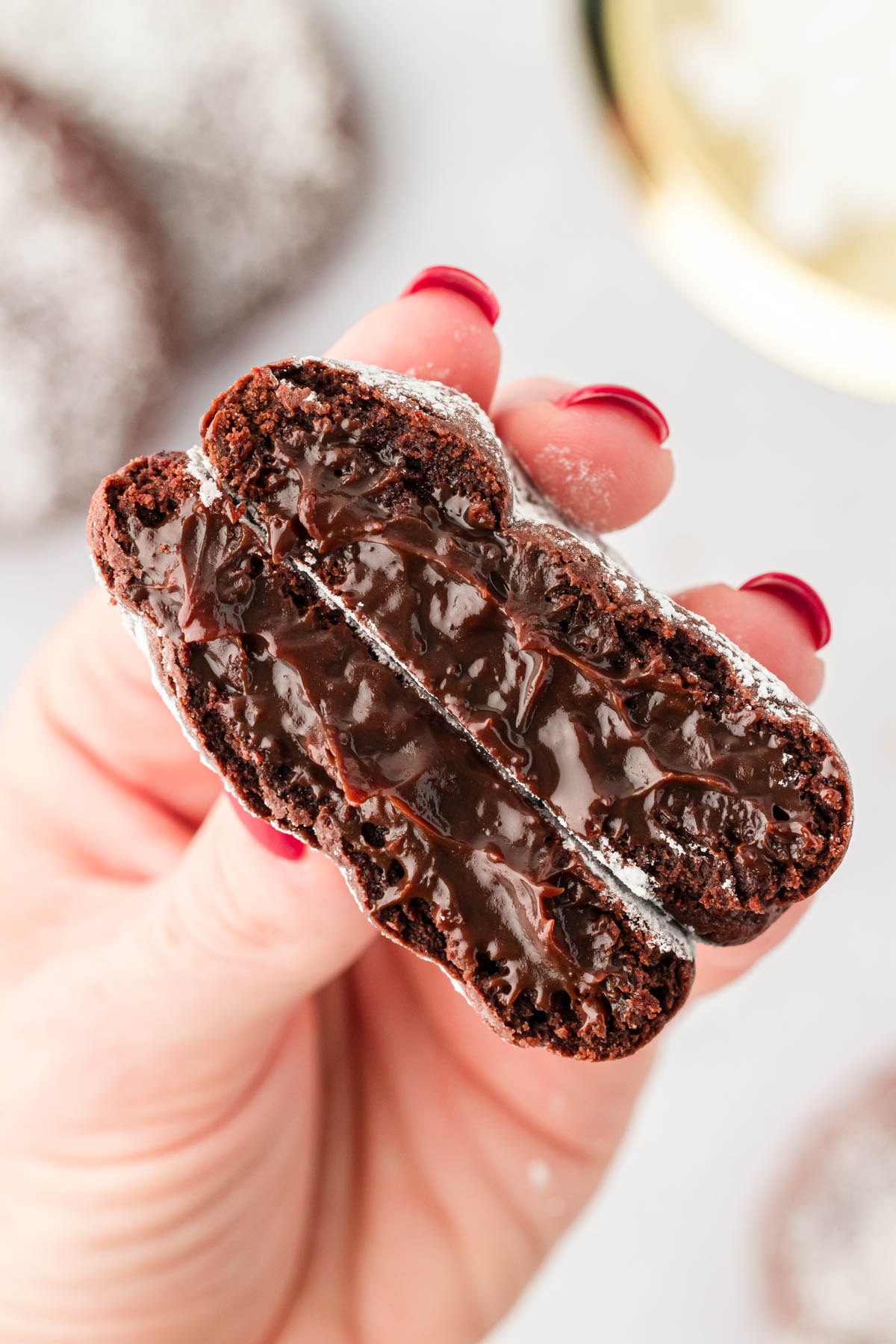 A woman's hand holding a lava cake cookie that's been broken in half to the camera.