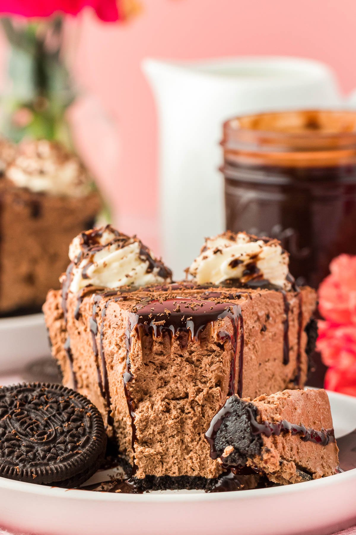 A slice of chocolate cheesecake on a white plate with a bite missing.