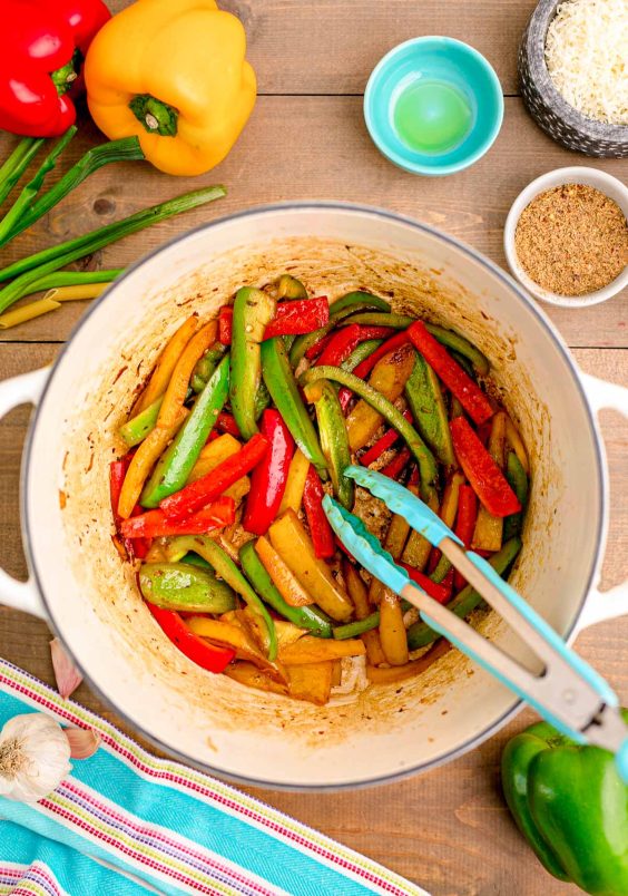Sliced bell peppers being cooked in a Dutch oven.