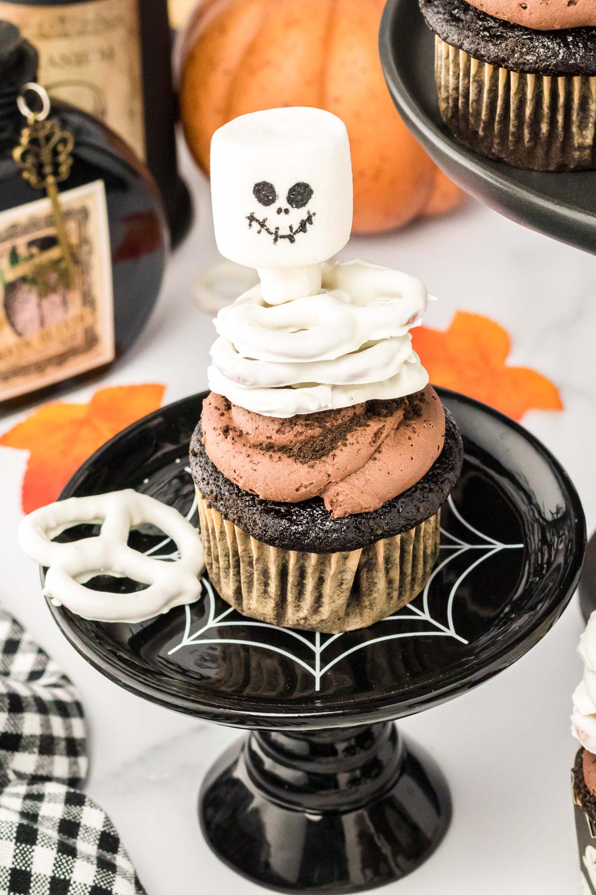 A chocolate skeleton cupcake on a black cake stand. 