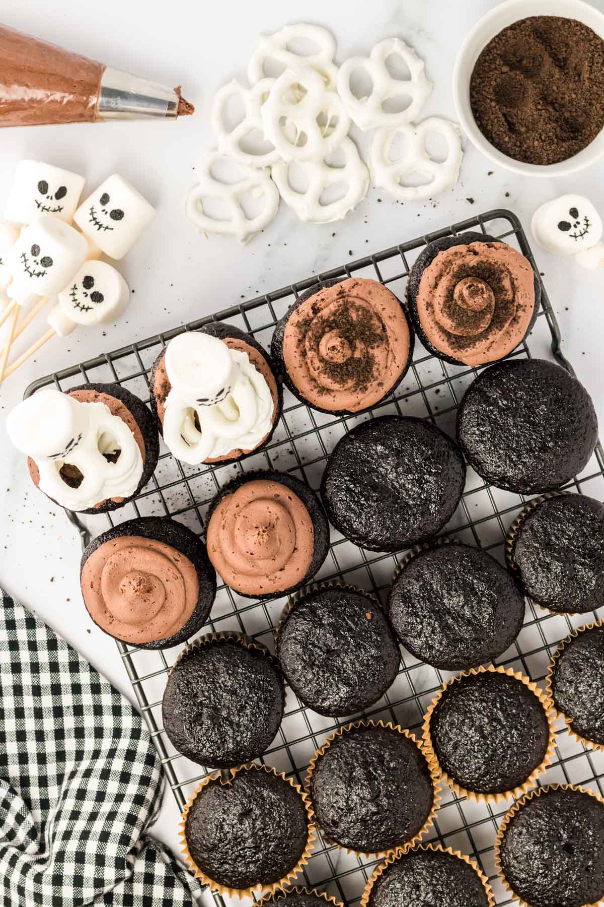 Skeleton cupcakes being prepared and assembled on a wire rack.