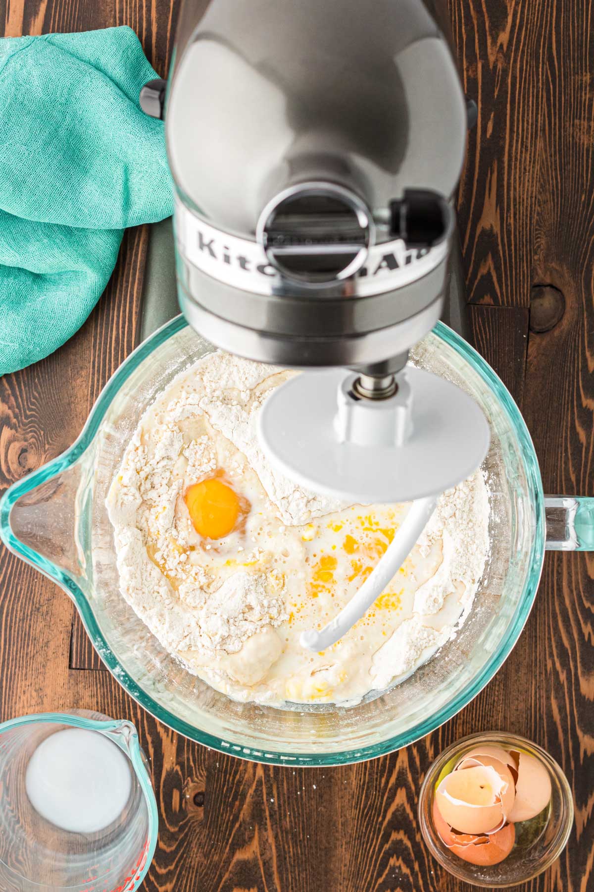 Milk and eggs being added to dry ingredients in a bowl to make cinnamon roll dough.