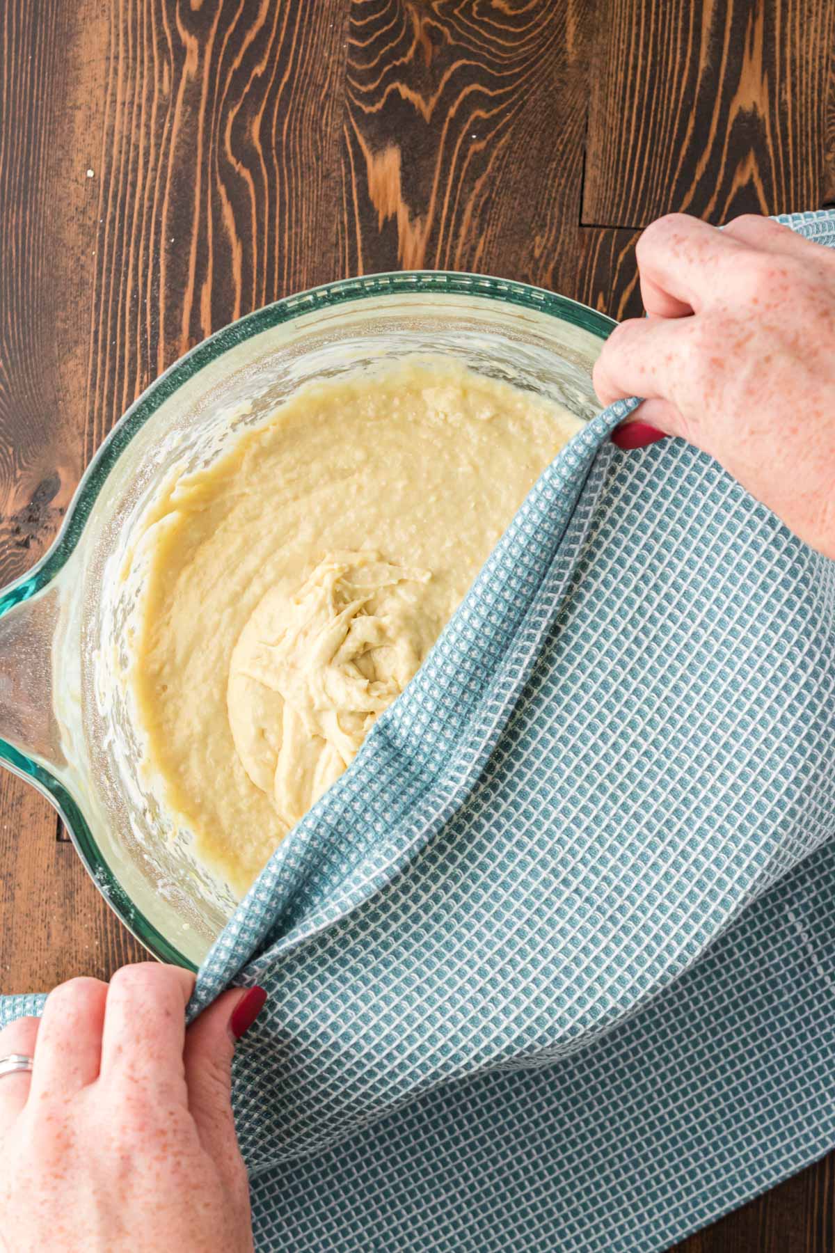 A stand mixer bowl being covered with a kitchen towel.