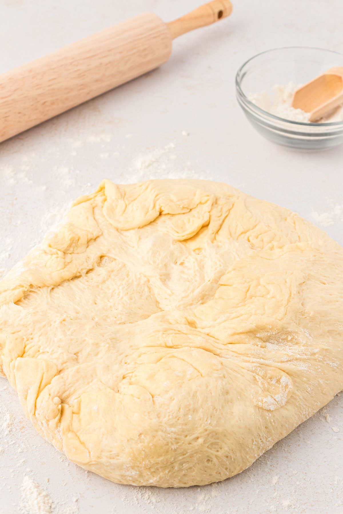 Cinnamon roll dough on a floured surface.