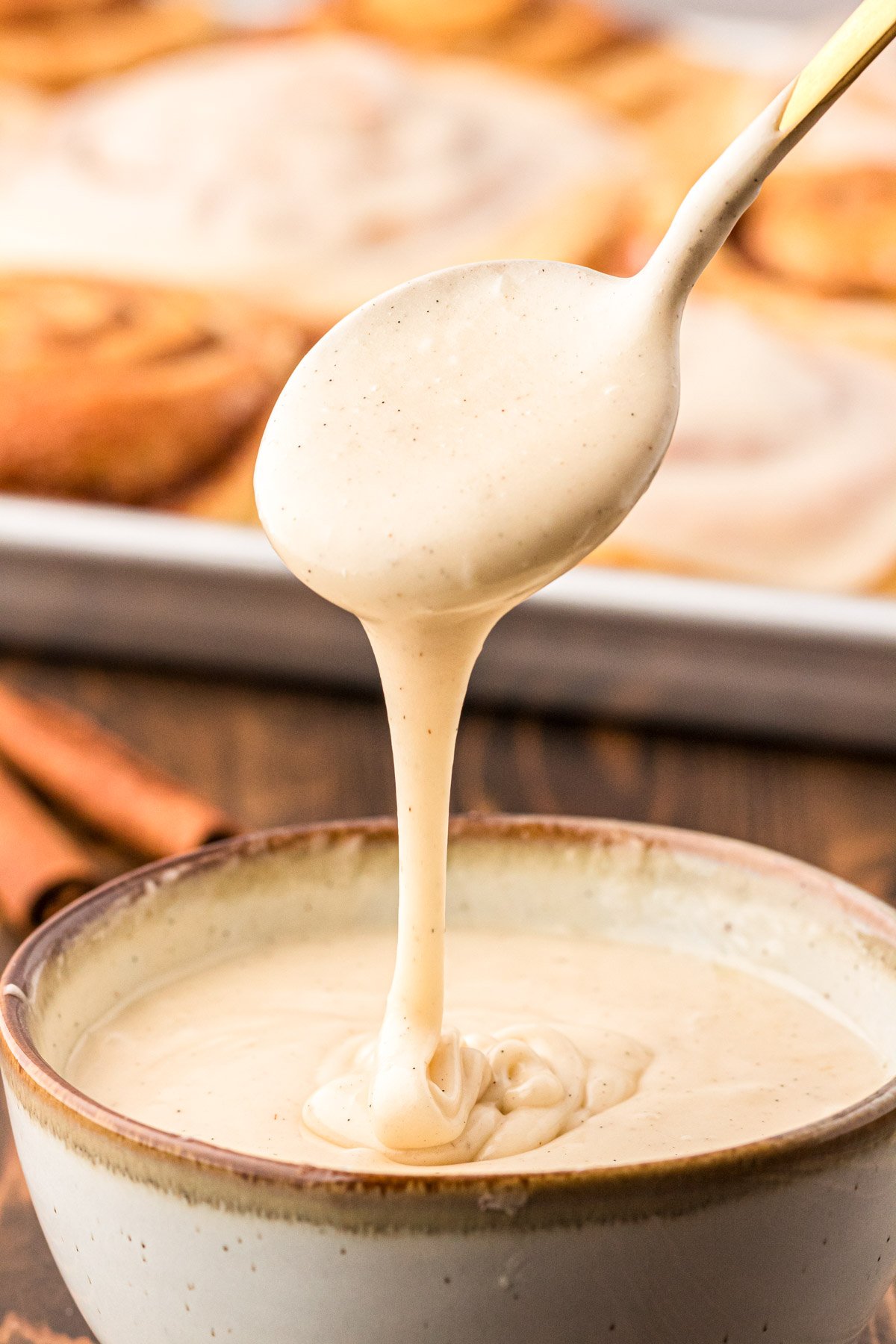 Vanilla bean icing being spooned out of a bowl.