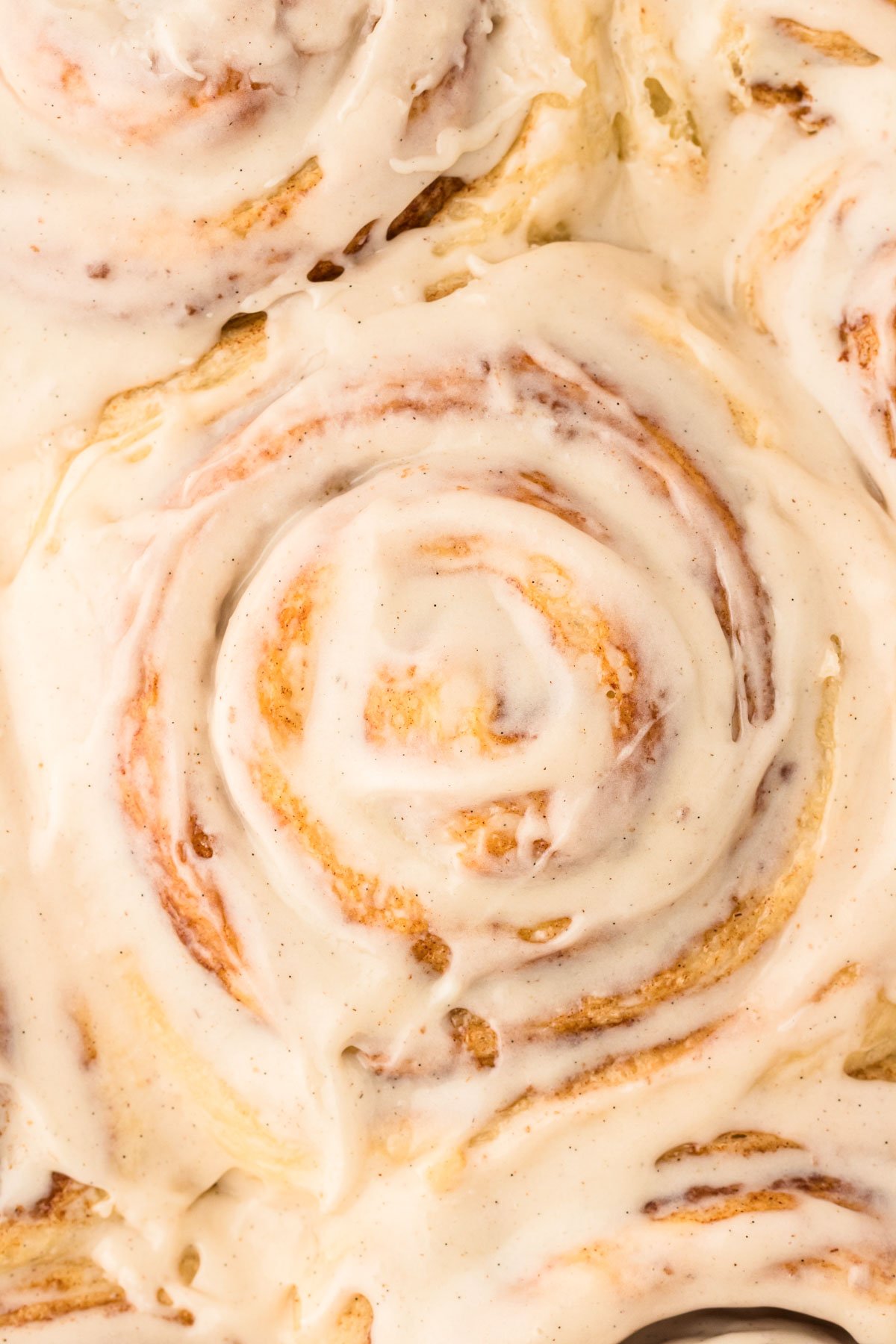 Overhead close up photo of cinnamon rolls in a ban covered with icing.