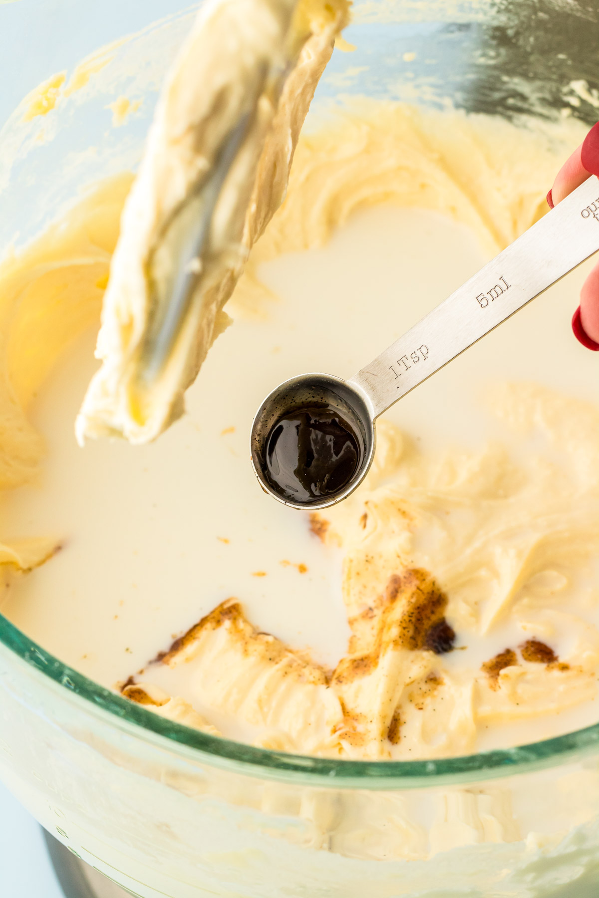 Vanilla bean paste and milk being added to cake batter.