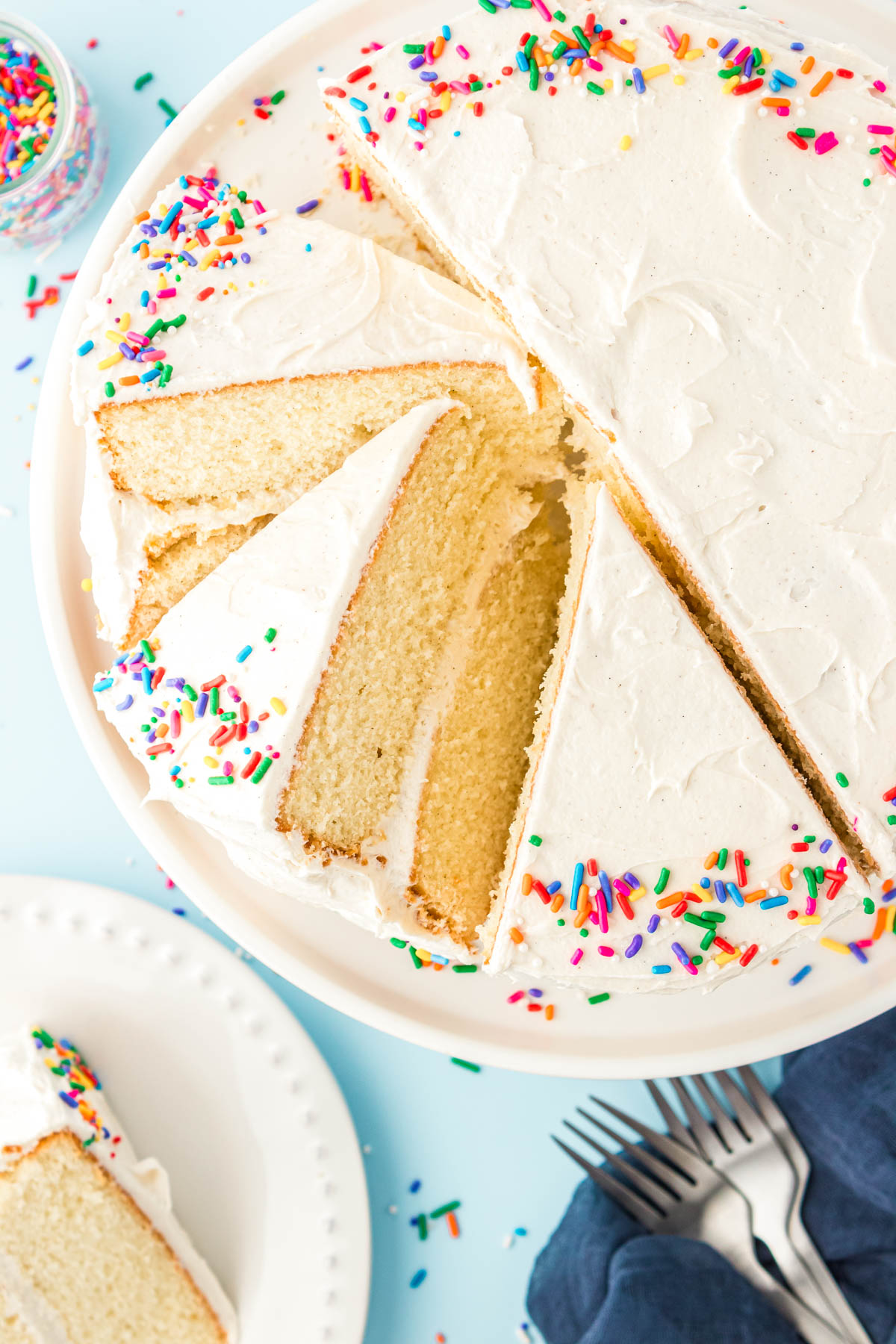 Overhead photo of a white layer cake, some slices are cut and leaning at an angle.