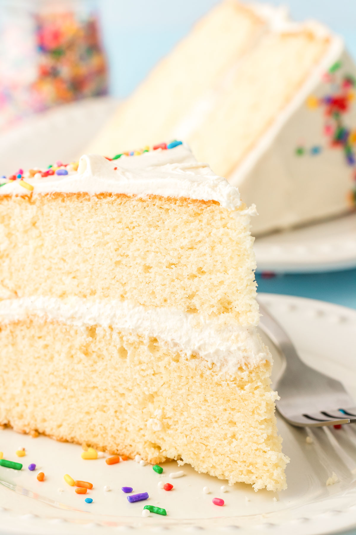 Close up of a piece of vanilla cake on a white plate.