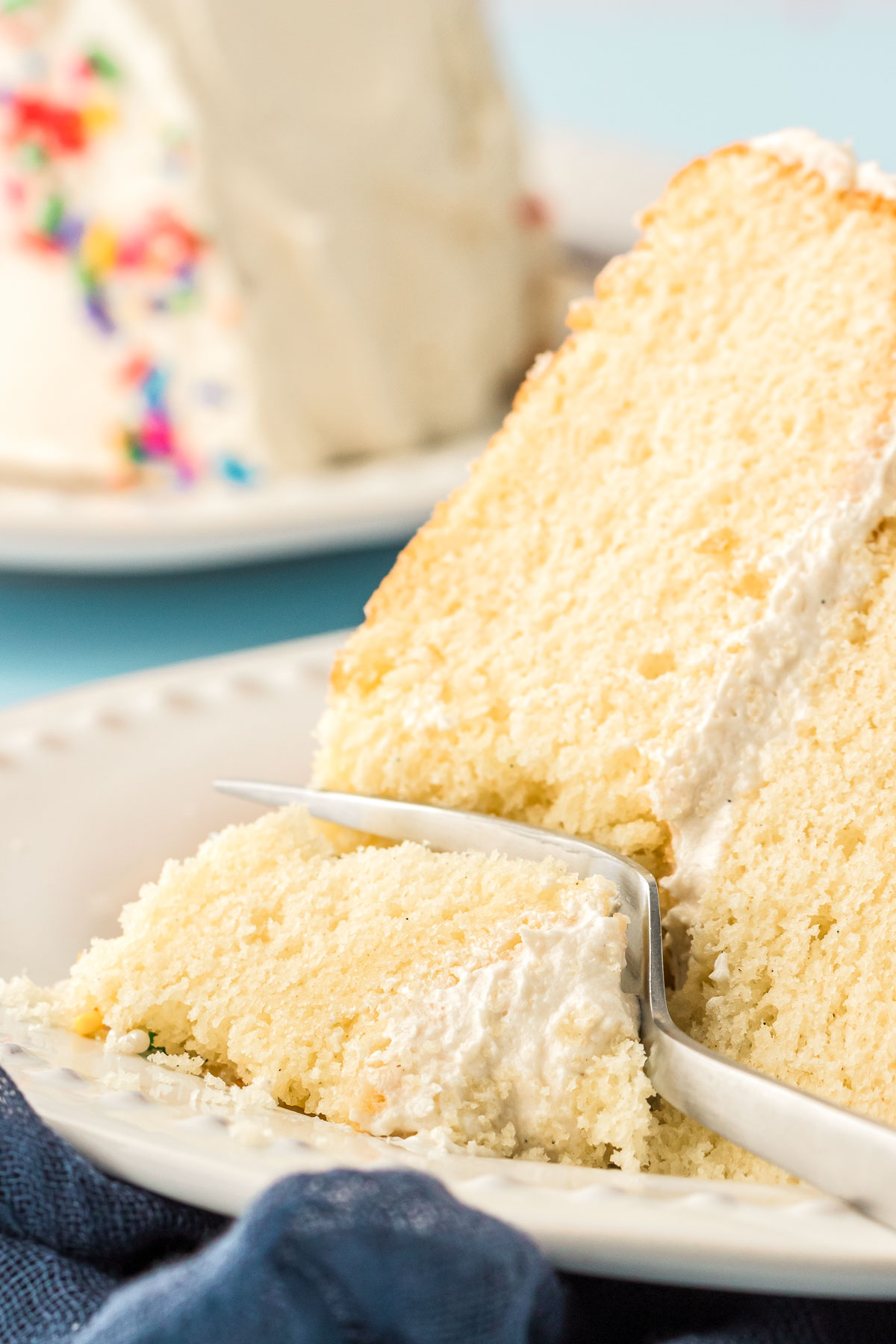 A fork taking a bite of white vanilla cake.