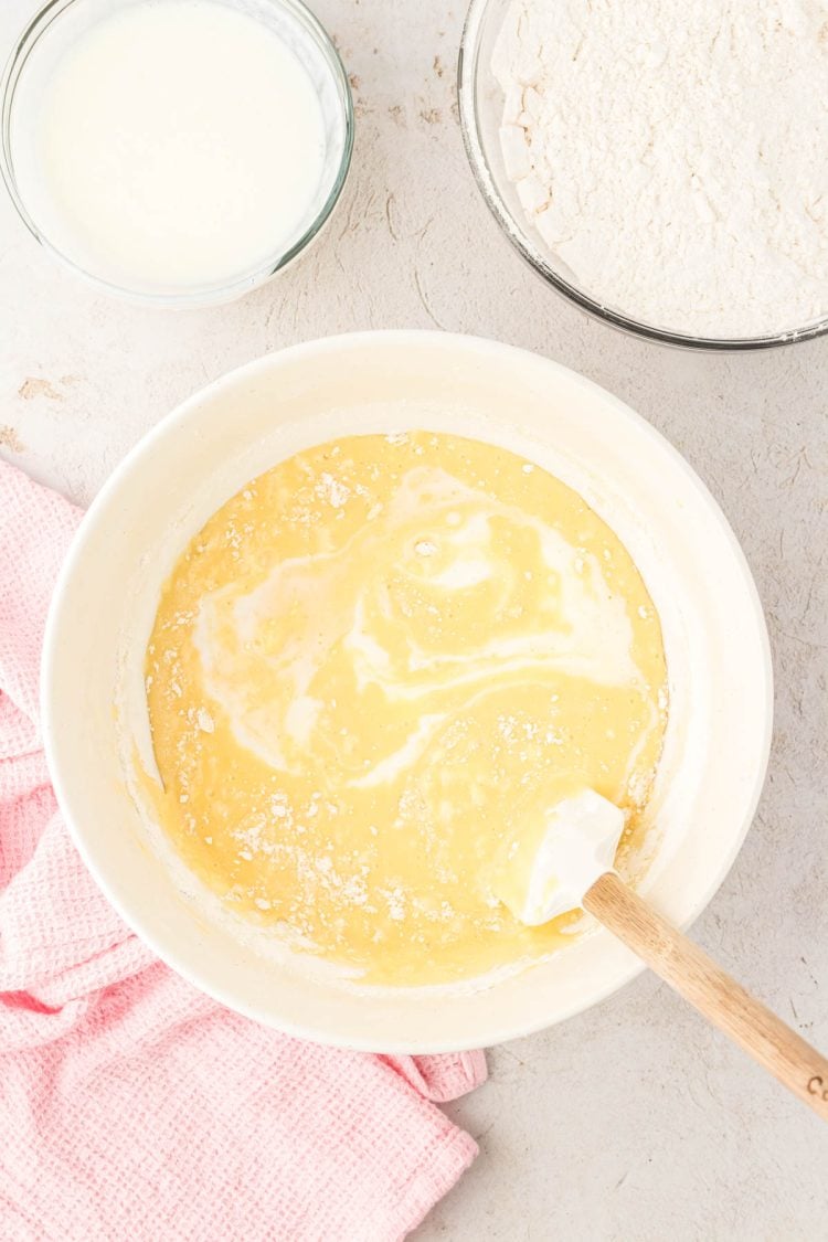 Buttermilk being folded into yellow cupcake batter.