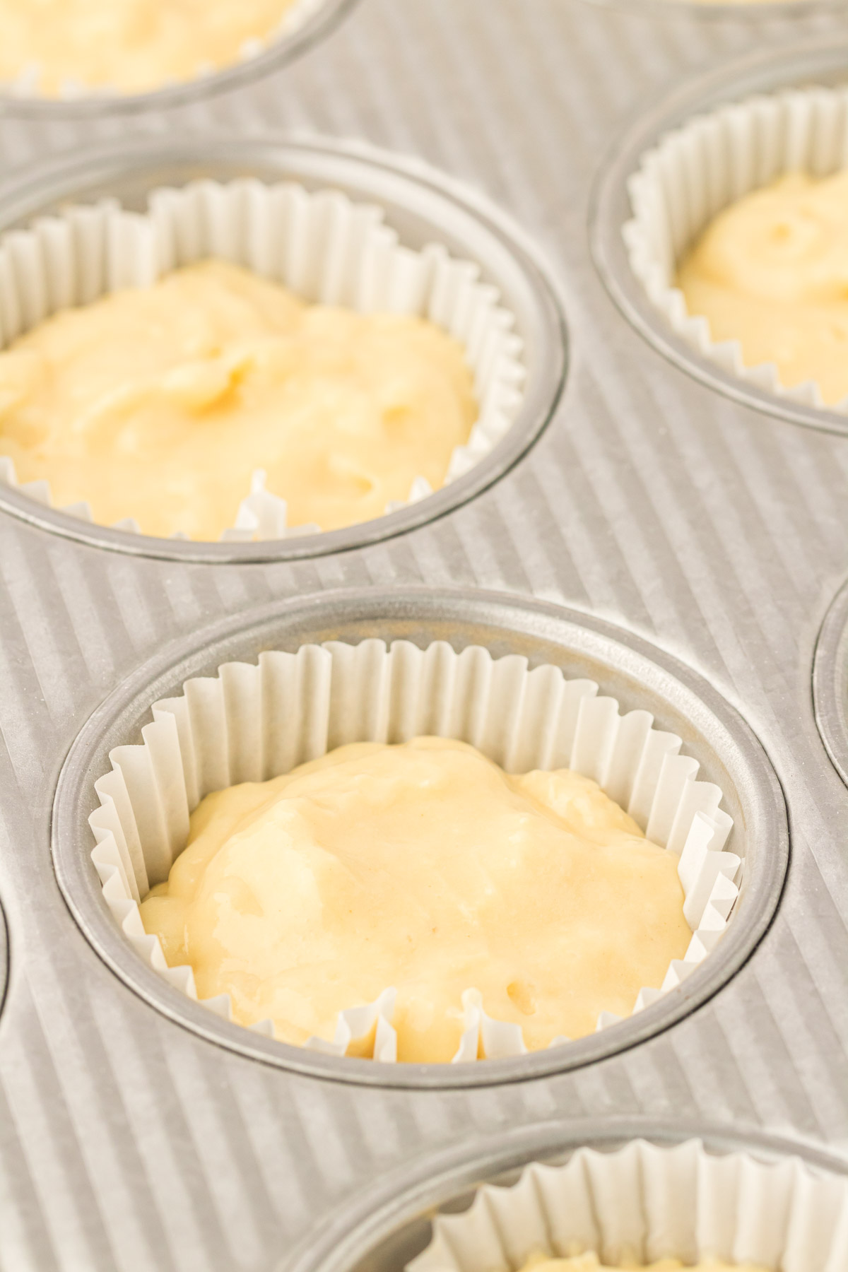 Yellow cupcake batter in a cupcake pan ready to be baked.