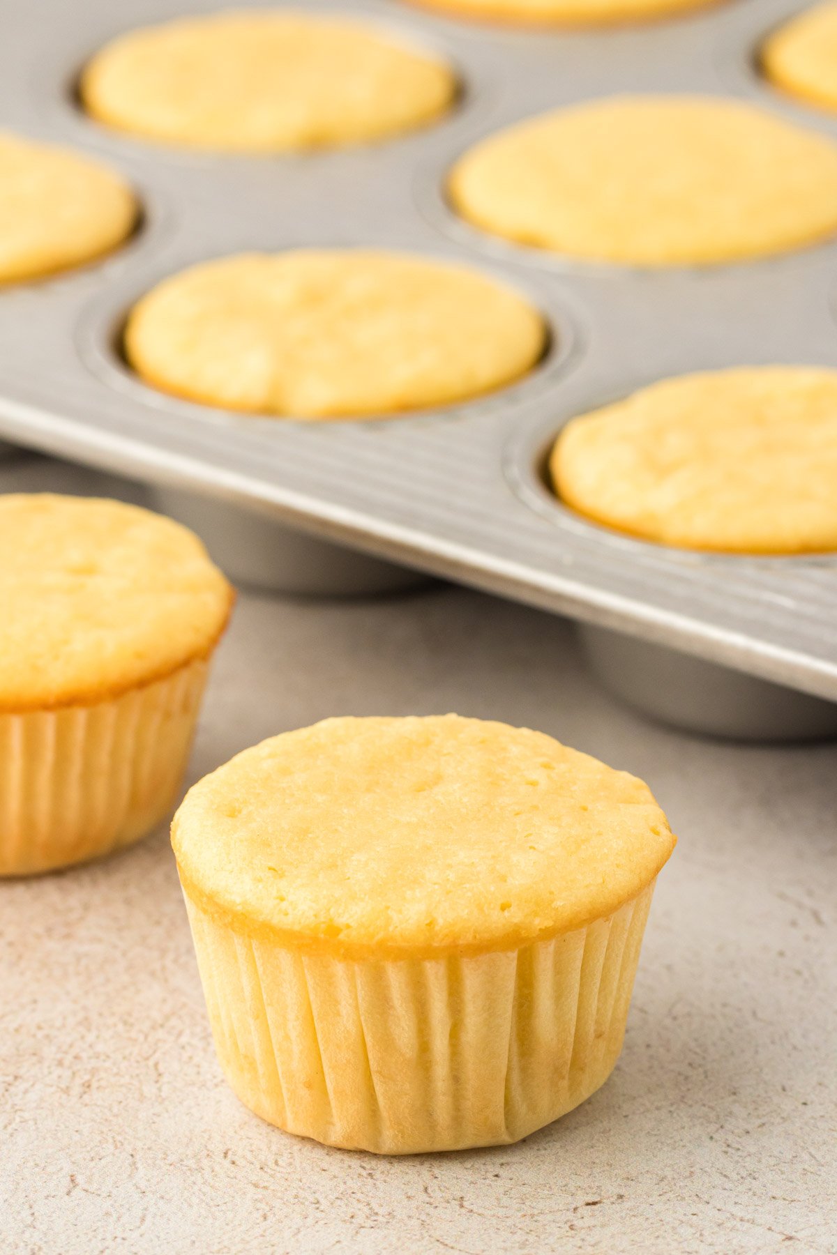Yellow cupcakes in and near a pan.
