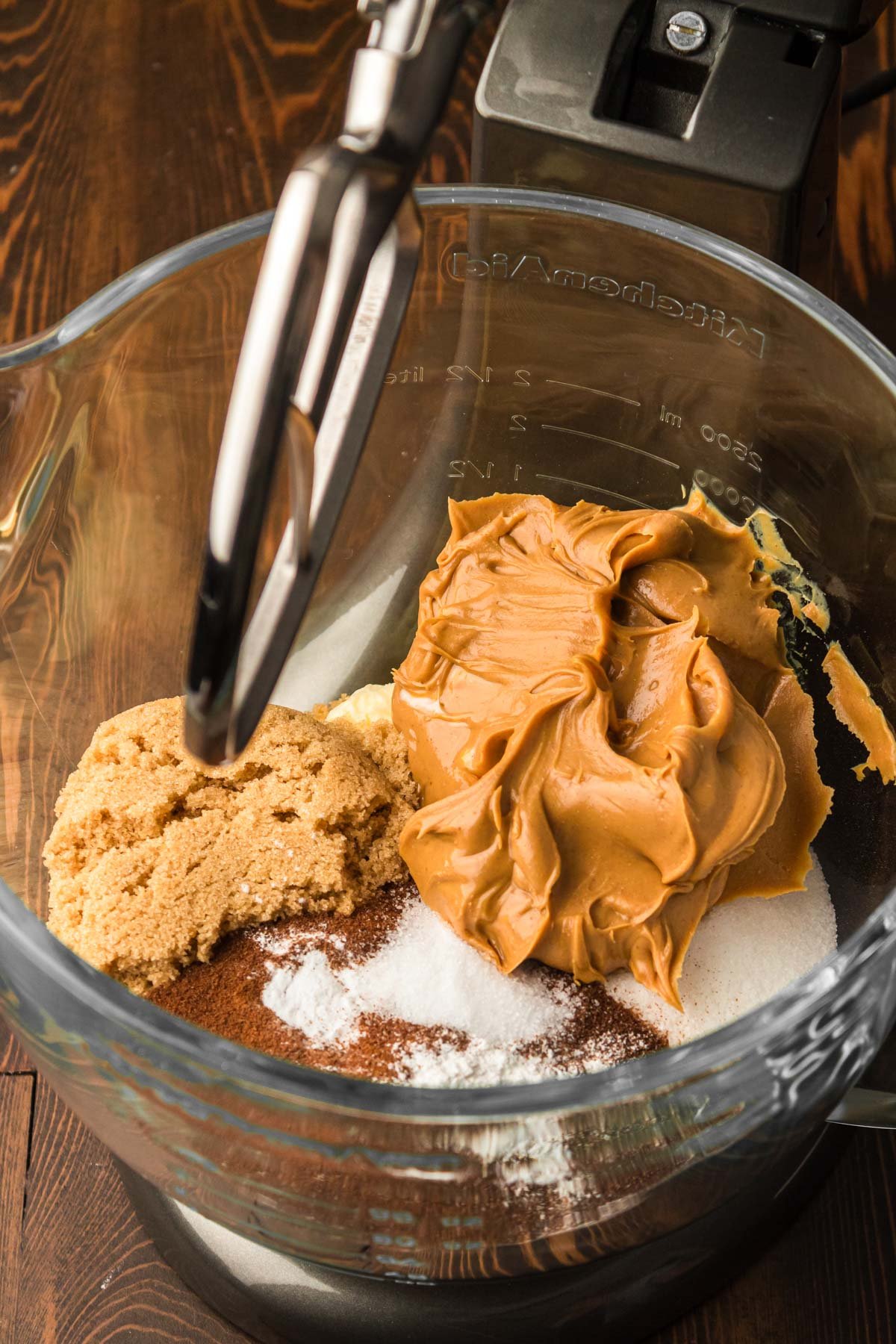Peanut butter, sugar, coffee grounds and other ingredients in a class stand mixer bowl.