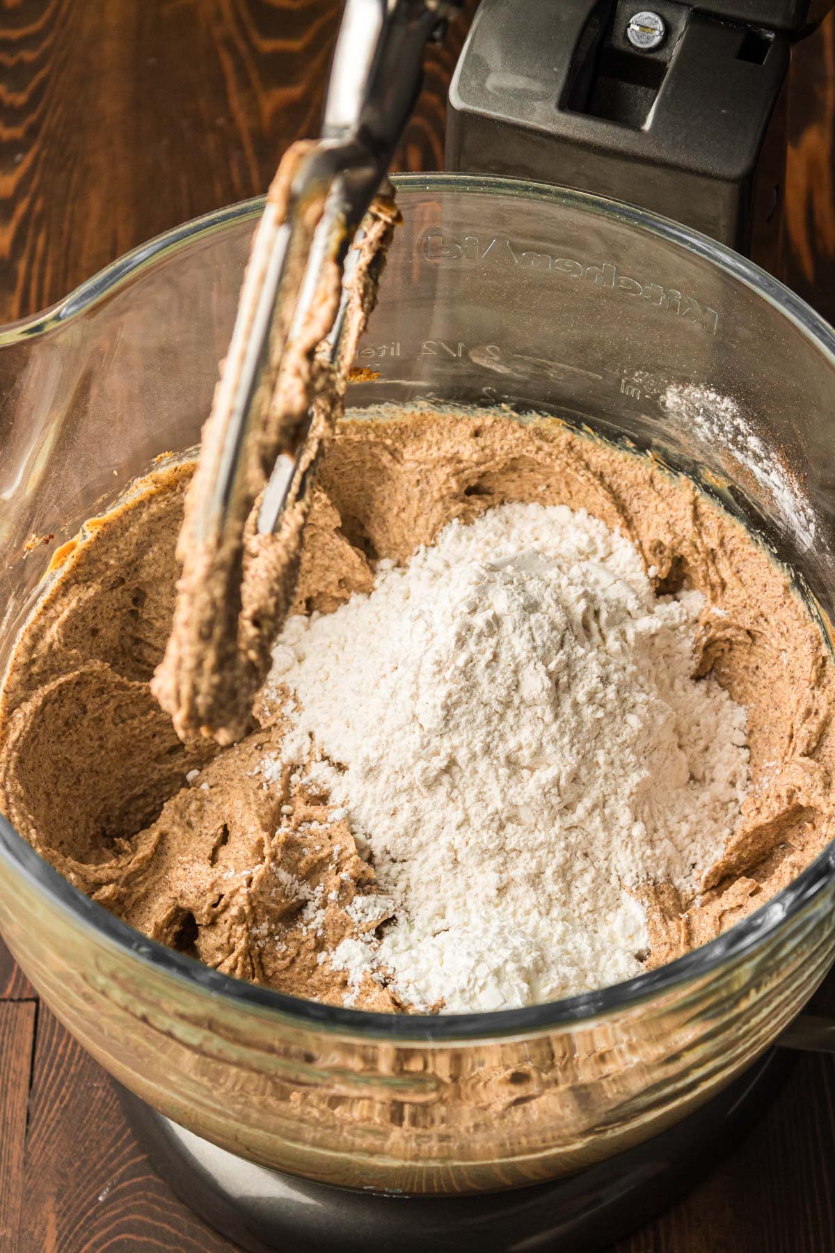 Dry ingredients being added to wet ingredients in a stand mixer bowl.