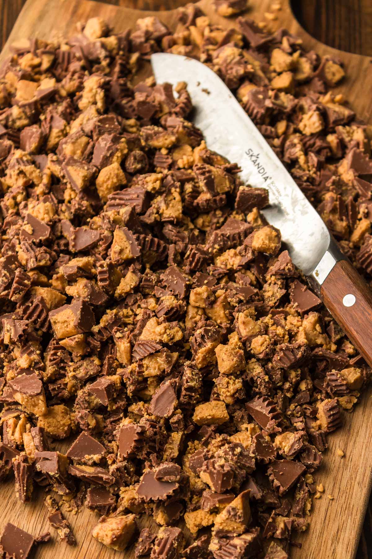 Peanut butter cups chopped up on a wooden board.