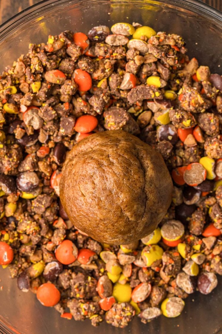 Peanut butter cold brew cookie dough in a bowl of Reese's Pieces and chopped peanut butter cups ready to be rolled.