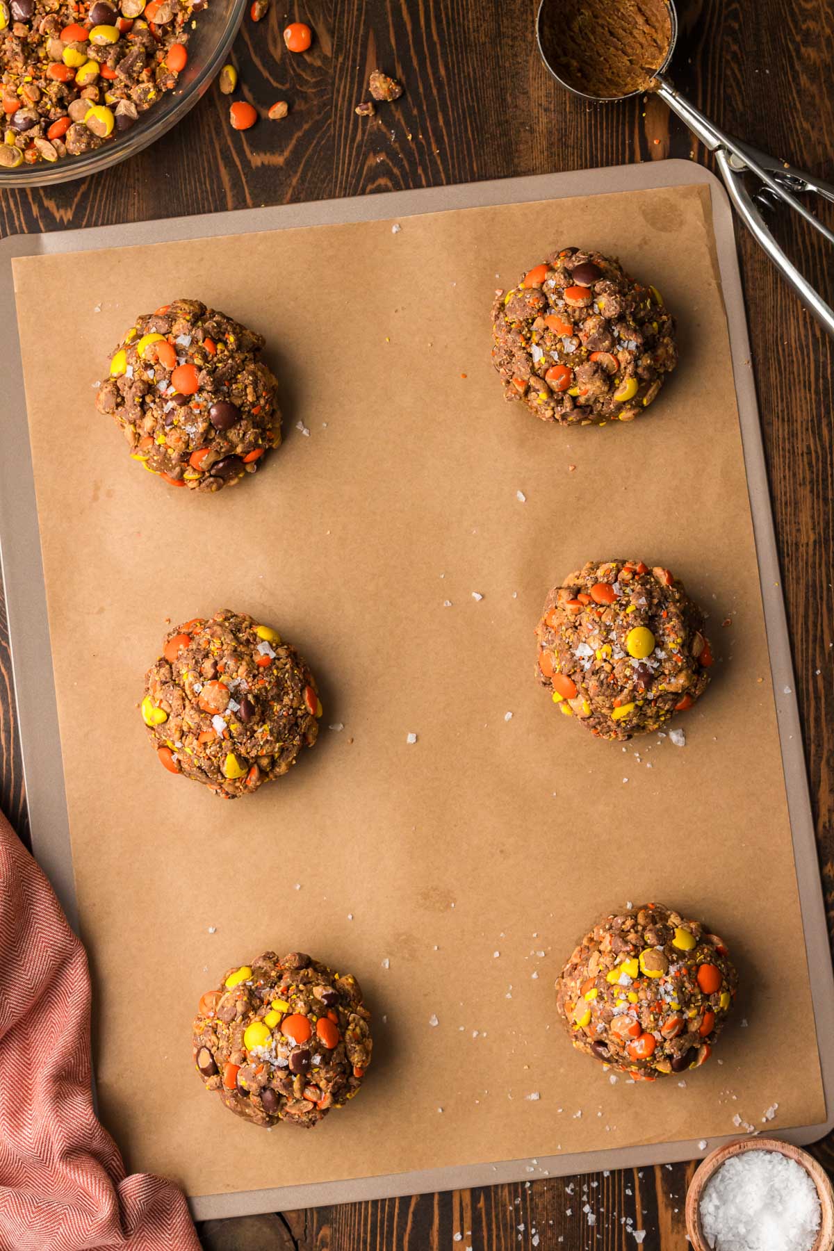 Large peanut butter espresso cookies on a parchment lined baking sheet ready to bake.