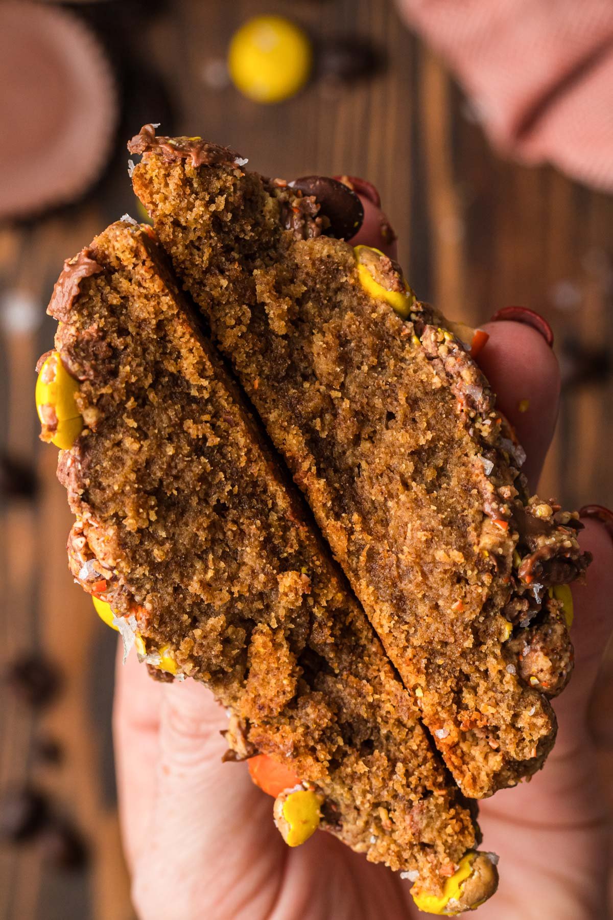 A woman's hand holding a Peanut Butter Espresso Cookie that's been split in half.